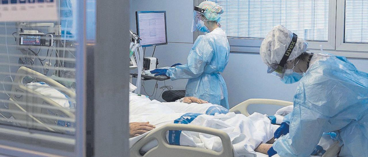 Dos sanitarias atienden a un paciente en una unidad COVID de un hospital. | // G. SÁNCHEZ