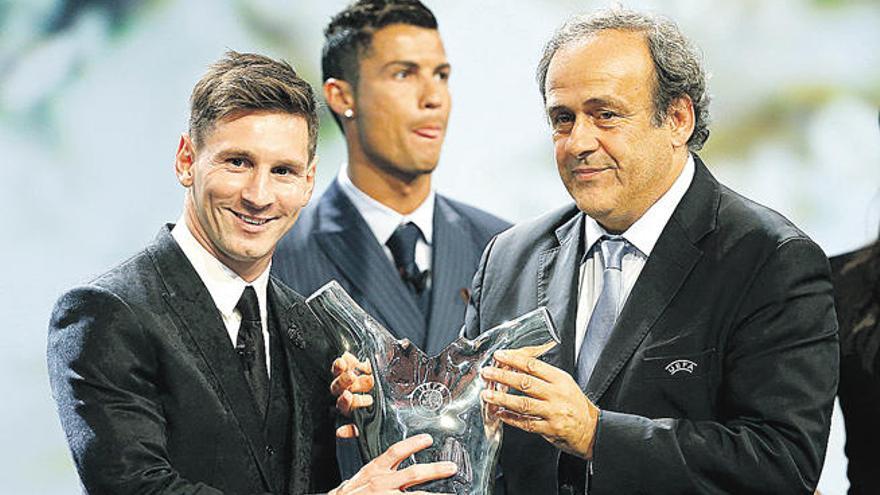 Messi recibe el trofeo de manos de Platini mientras Cristiano Ronaldo mira para otro lado.