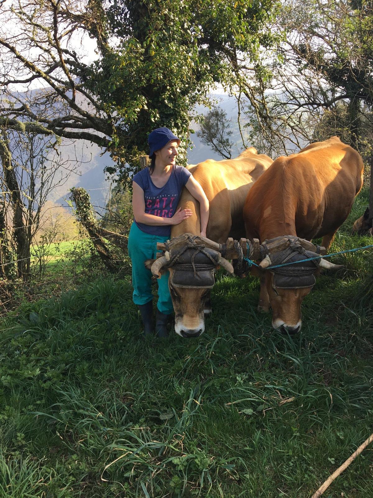Una mujer de una explotación ganadera, junto a dos de sus vacas.