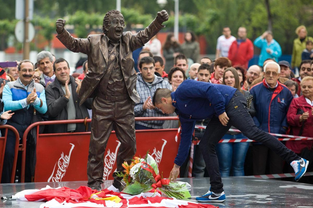 Manu Preciado deposita un ramo de flores a los pies de la estatua de su padre.