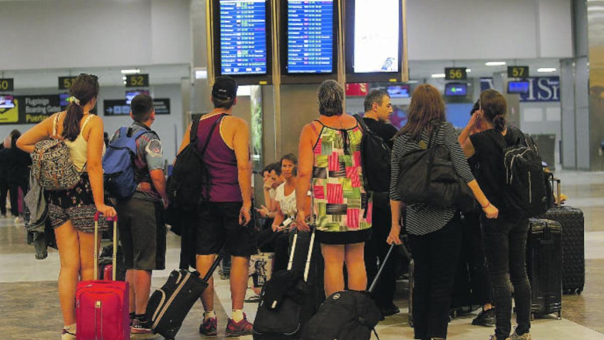 Un grupo de turistas observa los paneles de vuelos del Aeropuerto Tenerife Sur-Reina Sofía.
