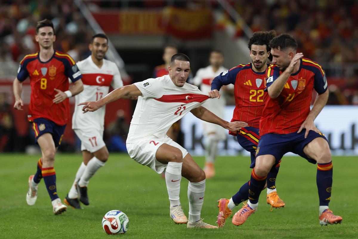 SEVILLA, 18/11/2025.- El delantero de Turquía, Deniz Gül (i), disputa el balón ante los jugadores de la selección española, Marc Cucurella y Aymeric Laporte, durante el encuentro correspondiente a la fase de clasificación para el Mundial 2026 que disputan hoy martes España y Turquía en el estadio de La Cartuja, en Sevilla. EFE / Julio Muñoz.