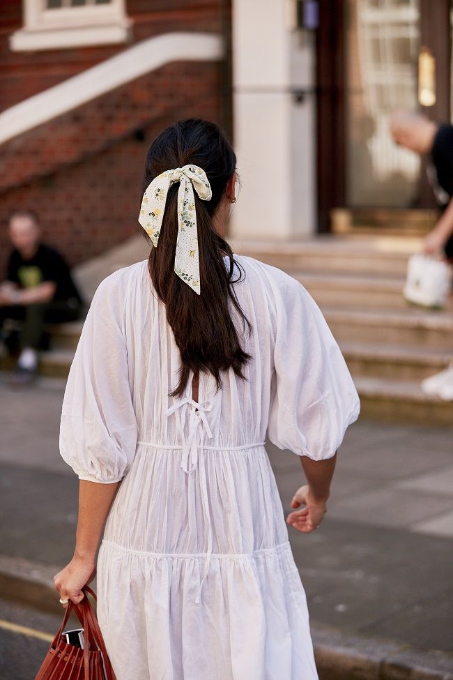 Look de vestido blanco y coleta con lazo, visto en el 'street style' de Londres