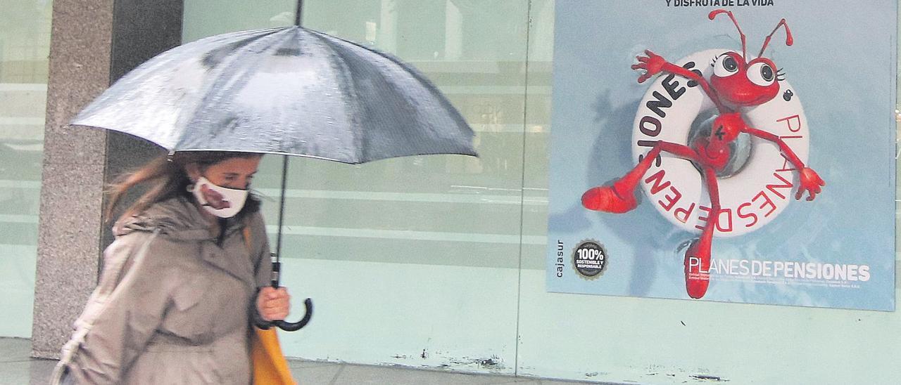 Una mujer pasa ante un cartel con publicidad de planes de pensiones.