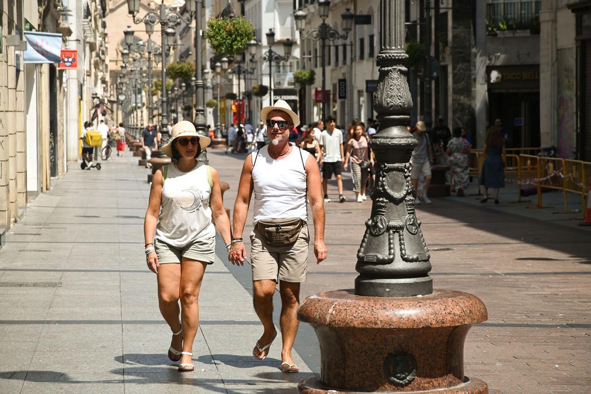 Dos personas paseando al sol por la calle Alfonso de Zaragoza