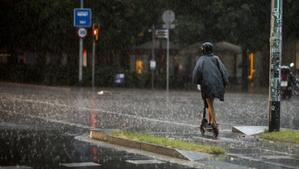 Un patinete circula bajo la lluvia durante un episodio de tormenta sobre la ciudad de Barcelona a primera hora.