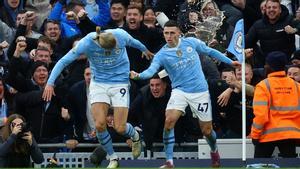 Haaland arrastra a Foden tras anotar este el gol del empate mientras, detrás, sale una cerveza volando.