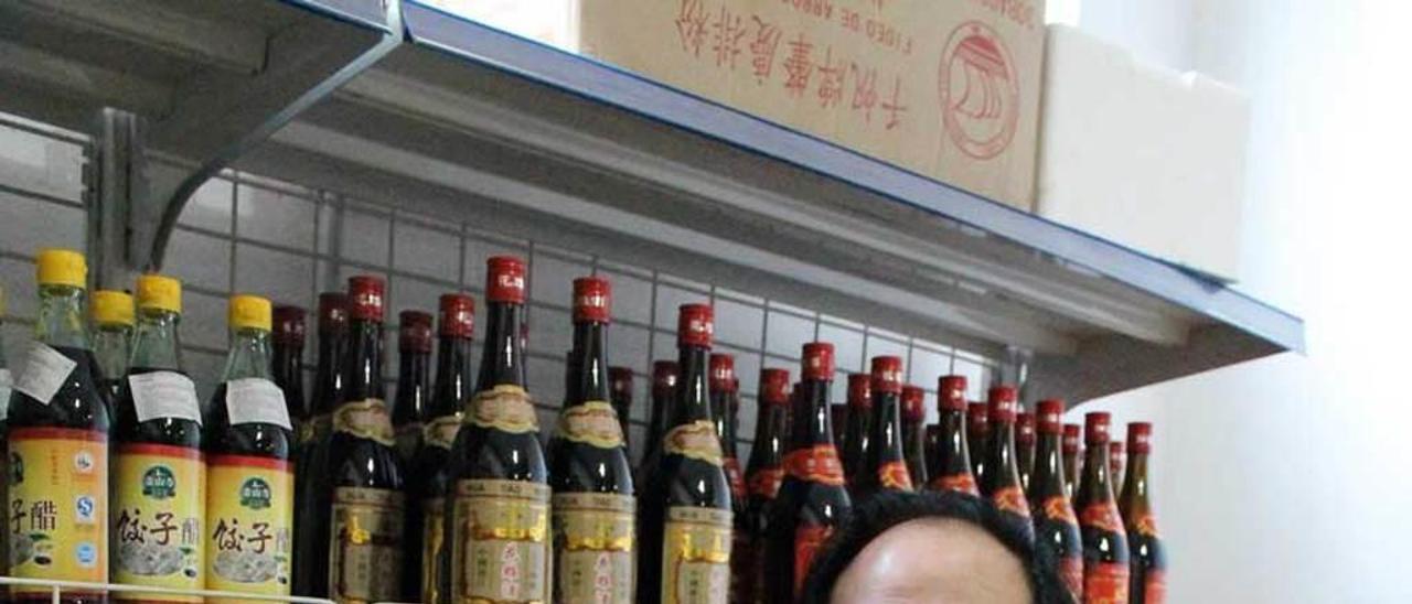 Carlos Zhang, con una botella de vino chino, en su tienda de Lugones.