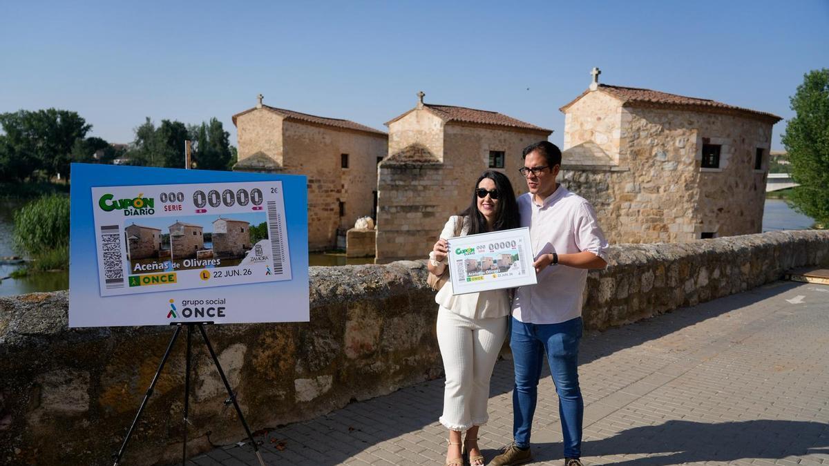 En primer término el cupón y responsables de la ONCE y del Ayuntamiento con las aceñas de Olivares de fondo.