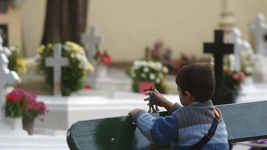 Un niño juega con un muñeco en el cementerio de San Amaro el Día de Difuntos. / víctor echave