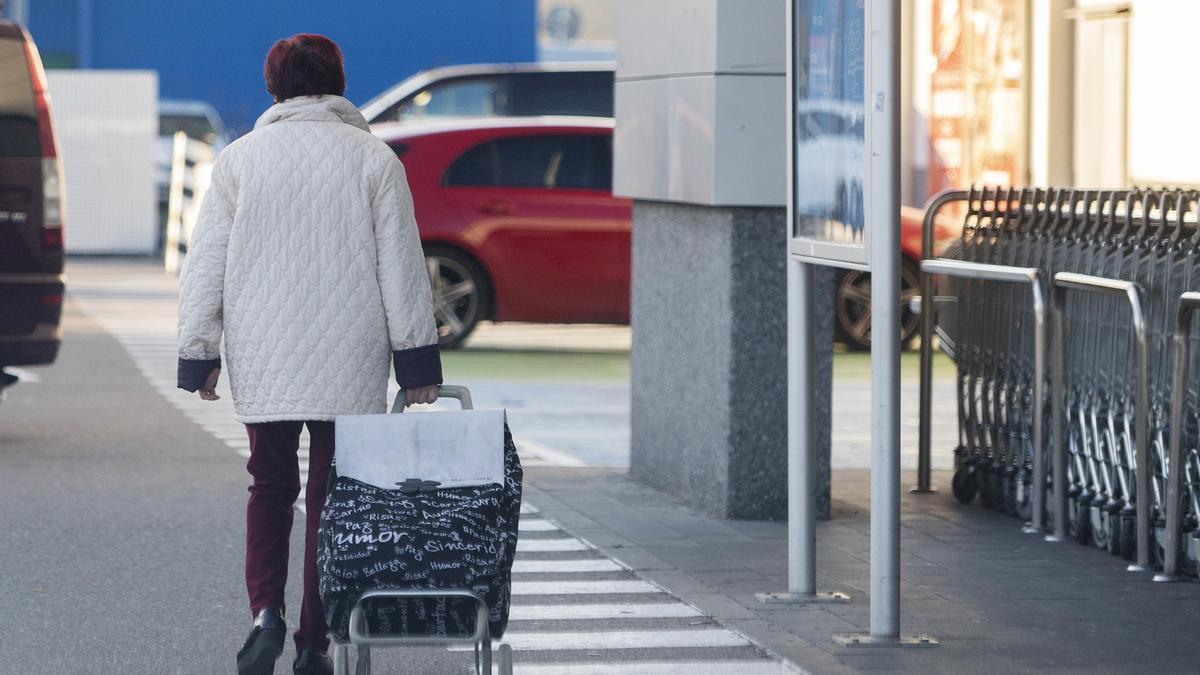 Una mujer sale del supermercado con un carro de la compra