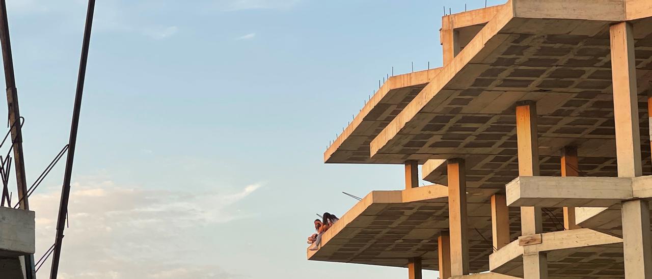 Unos jóvenes sentados en el tercer piso de la estructura.