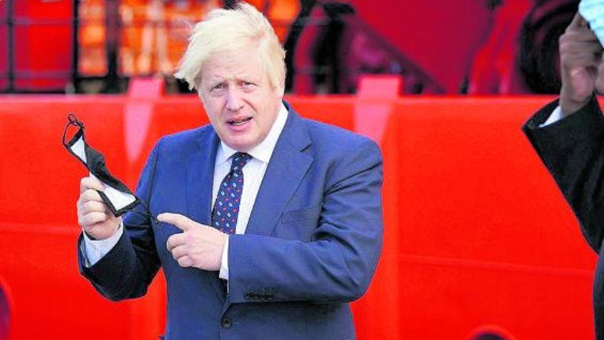 El ‘premier’ británico, Boris Jonhson, sostiene una mascarilla durante la visita que realizó ayer a un puerto militar escocés.