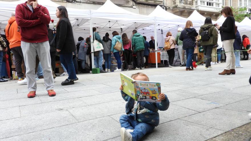 Un niño ojea un cuento frente la carpa del Día del Libro, en la calle Paseo.  |  FERNANDO CASANOVA