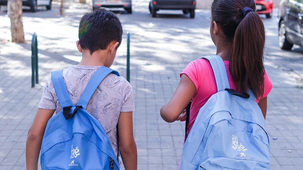 Dos niños que participan en el proyecto Chapotea, con las mochilas de CaixaProinfancia cargadas de material escolar
