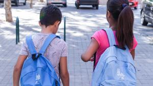 Dos niños que participan en el proyecto Chapotea, con las mochilas de CaixaProinfancia cargadas de material escolar.