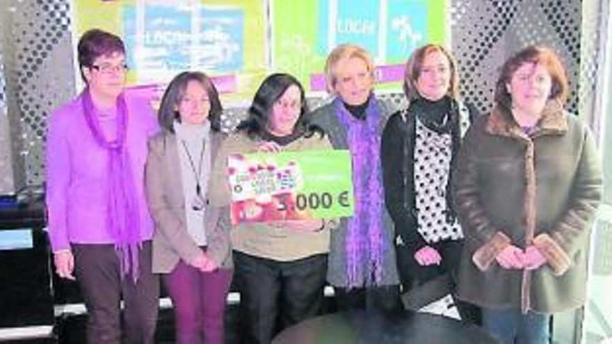 La premiada posa con el cheque, junto a comerciantes y a María Nachón.