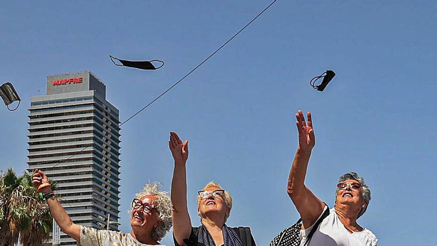 Tres dones llancen les mascaretes a l’aire a Barcelona. | JORDI OTIX