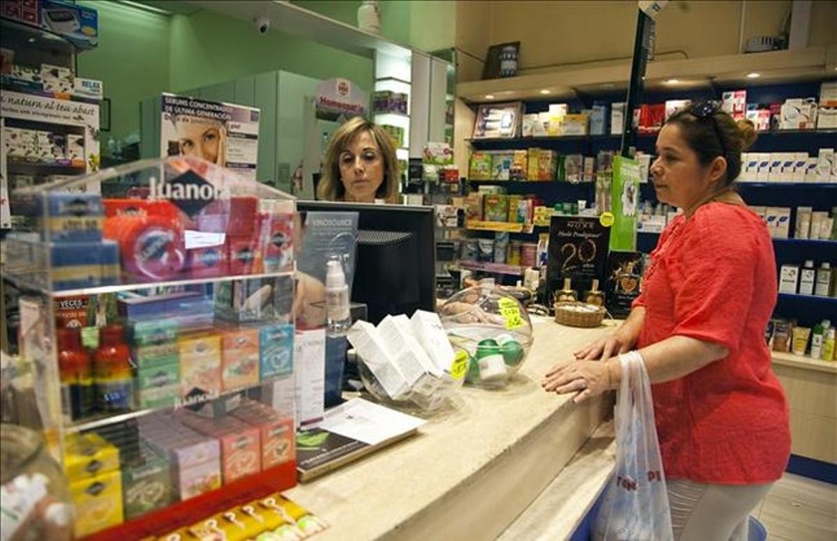 Una usuària compra medicaments amb recepta en una farmàcia de Barcelona. Una usuària compra medicaments amb recepta en una farmàcia de Barcelona.
