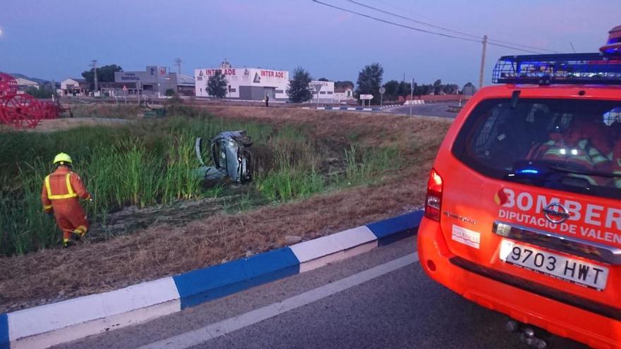 Los bomberos y, al fondo, el coche siniestrado.