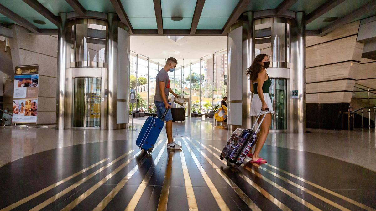 Una pareja de turistas camina con las maletas por el hall de un hotel en Benidorm.