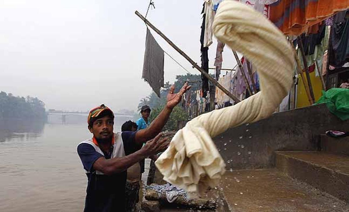 Un bugader fa la seva feina en un boirós matí a la riba del riu Kelani, a Colombo (Sri Lanka).