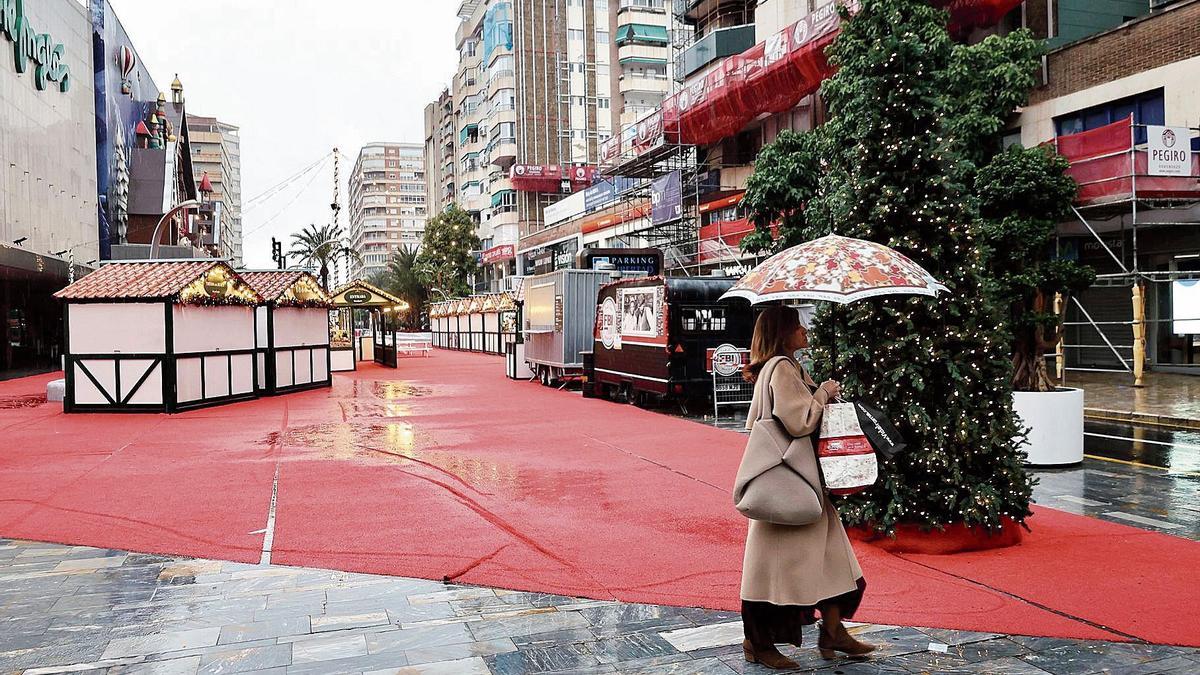Una mujer caminando ayer por el entorno de El Corte Inglés en Murcia con las casetas navideñas cerradas.