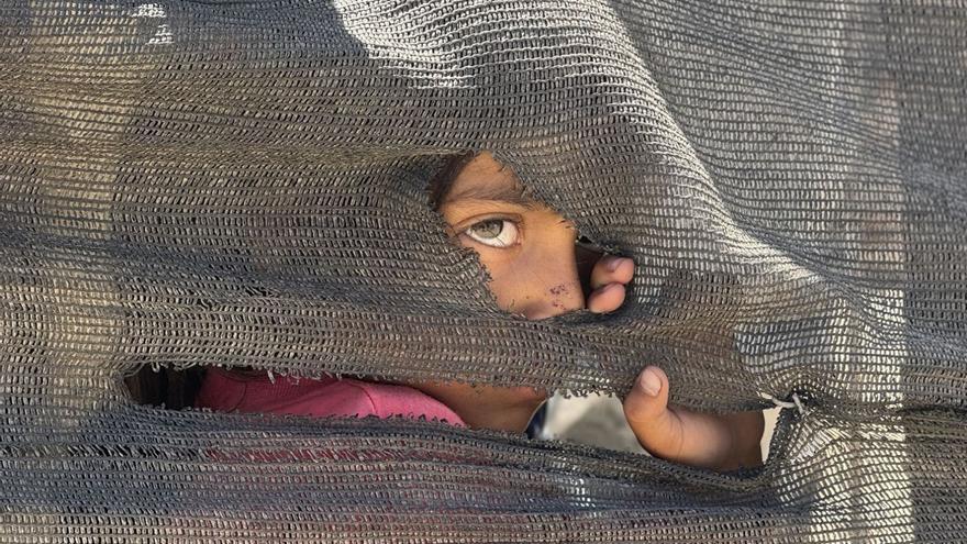 Unha nena asómase nunha tenda improvisada en Gaza.