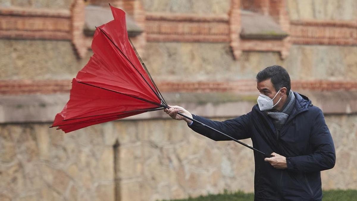 El presidente del Gobierno, Pedro Sánchez, usa un paraguas un día de viento.