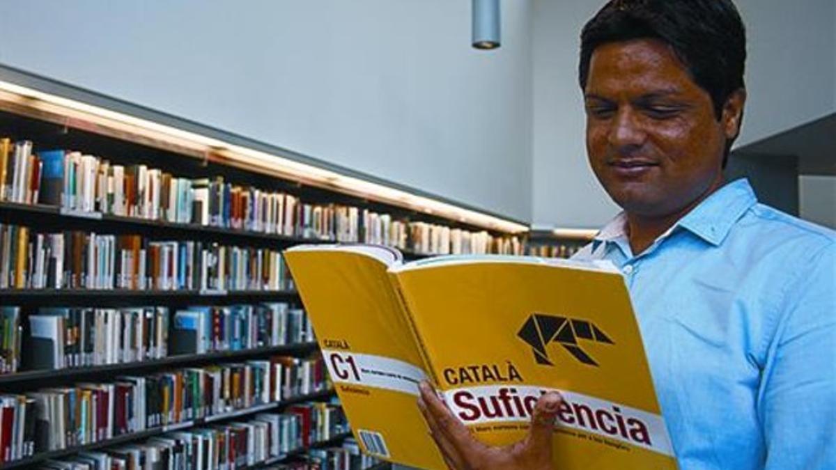En la biblioteca 8Sarfaraz Mehdi, posa con un libro de catalán.