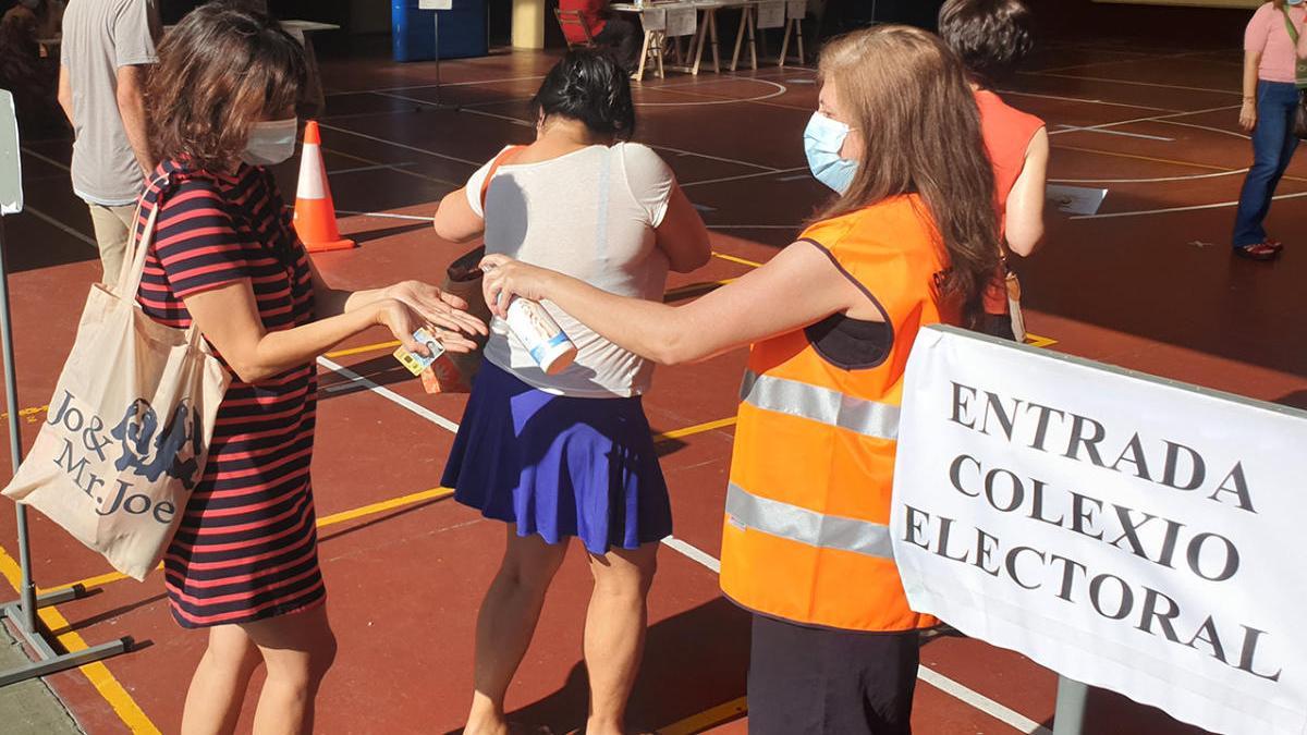 Una voluntaria dispensando gel hidroalcohólico a la entrada del colegio Salesiano, en Vigo, durante el 12-J. // Marta G. Brea