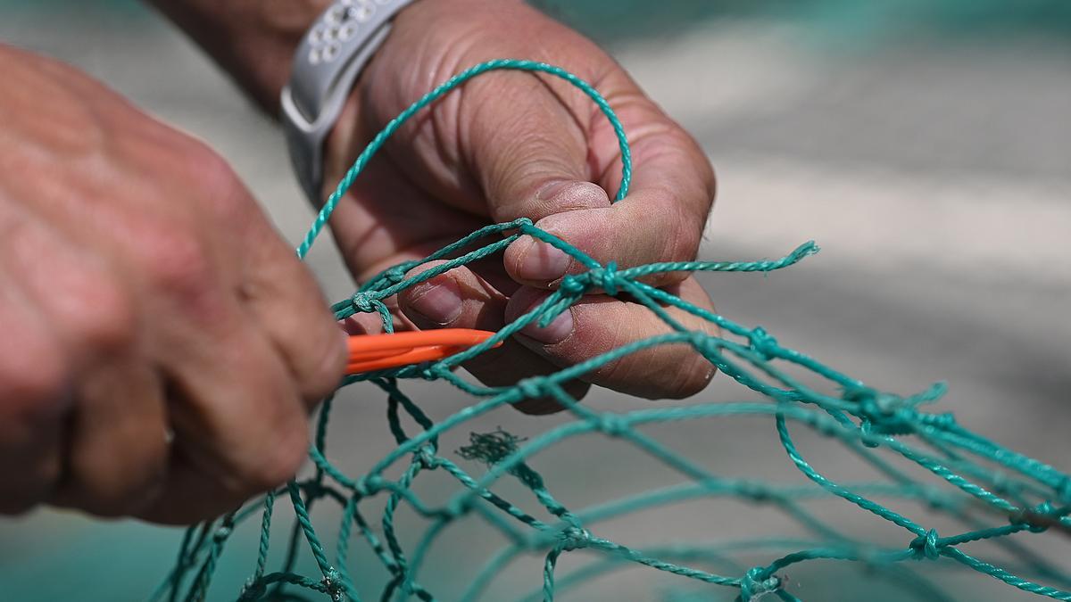 Las manos de Paquito, uno de los últimos ‘xarxaires’ de la Barceloneta, cosiendo las redes junto a la torre del reloj.