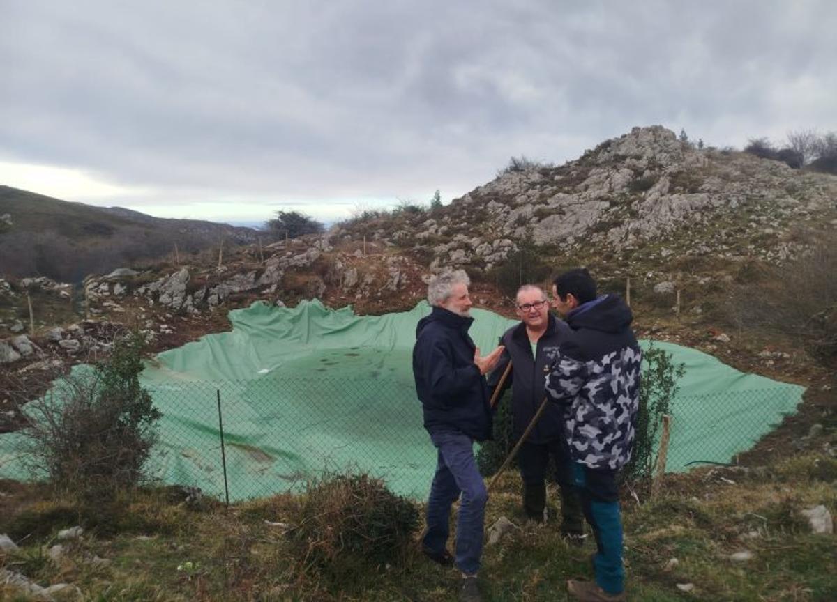 El concejal Xuan Valladares –izquierda– y dos ganaderos, junto a la balsa del monte del Ríu de Nueva.