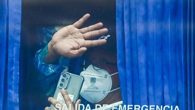 Un dels passatgers de l’MV Hondius saluda des d’un autobús després de desembarcar, diumenge. | JORGE GUERRERO / AFP