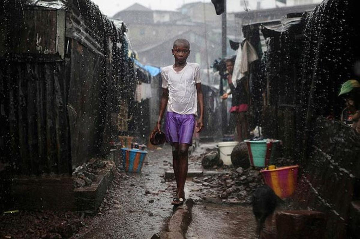 Un nen camina sota la pluja al barri de Susan’s Bay a Freetown (Sierra Leone). El govern de la nació ha qualificat el brot de còlera que sacseja el país com ’emergència nacional’. Al zenit de l’estació de pluges, les zones sobrepoblades amb deficients sistemes de clavegueram com Susan’s Bay contribueixen a estendre la malaltia.