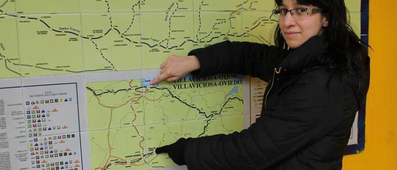 Yolanda Alegre señala Gijón y la Pola en un mapa de la estación de tren polesa.