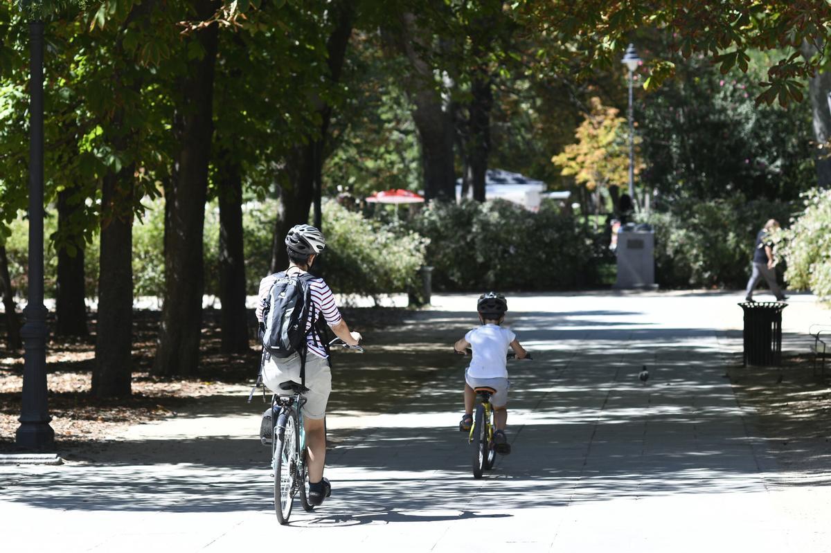 06/09/2019 Una madre y su hijo pasean en bicicleta en un parque de Madrid.