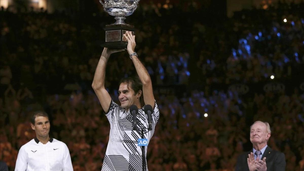 Federer alza la copa entre Nadal y el excampeón Rod Laver.