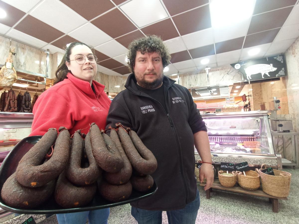 Sara Prado y Antonio Fernández muestran unos chorizos de vaca de su ganadería en la carnicería que regentan en Lugo.