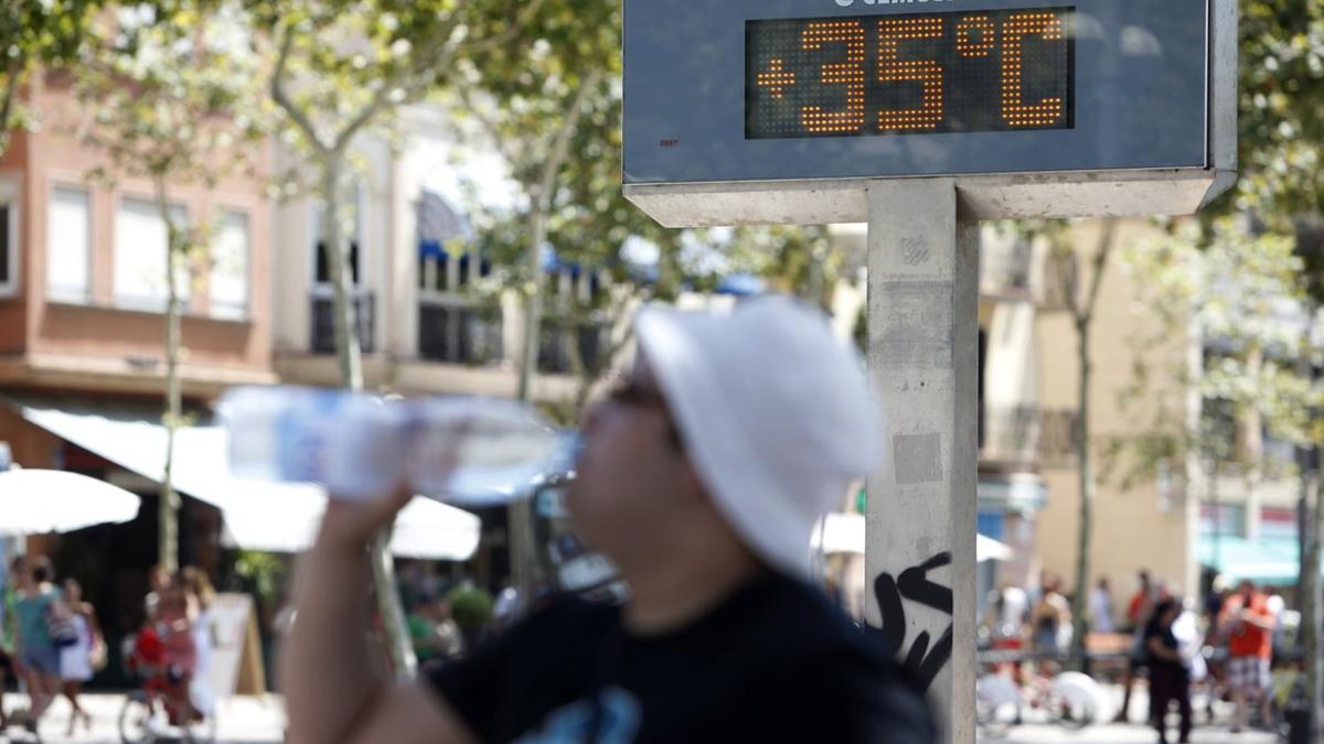 Un hombre bebe agua ante un termómetro que marca los 35 grados, en una imagen de archivo en Barcelona.