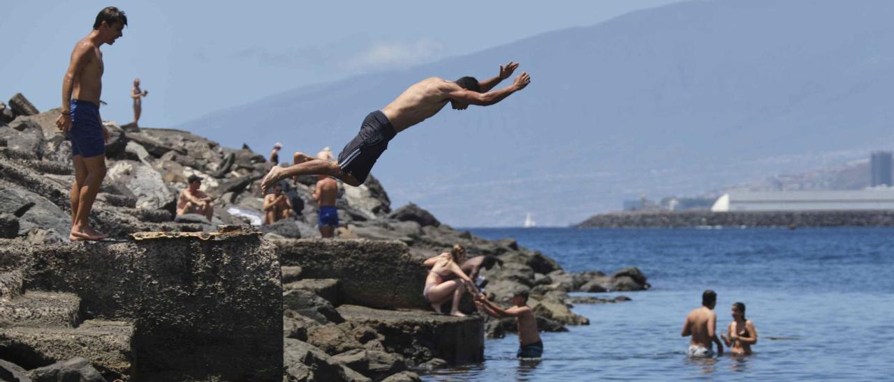 Un joven se lanza al agua en el espigón de la playa de Las Teresitas .