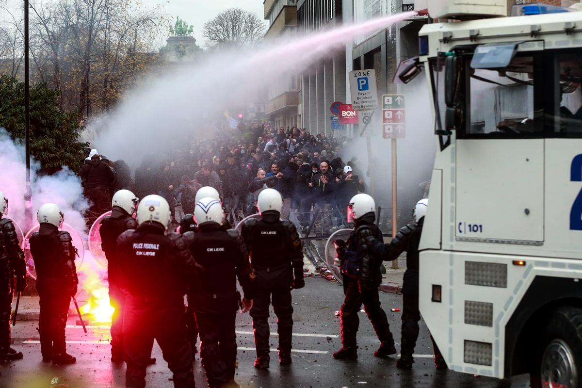 La policía intenta dispersar a los manifestantes con cañones de agua, durante una manifestación en Bruselas contra las medidas para atajar la pandemia.