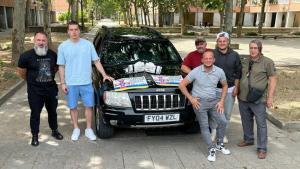 Andriy Modrystsky, Andriy Lunin y Roman Zozulia con uno de los 19 vehículos enviados a Ucrania