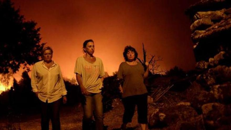 Tres vecinas de la aldea de Toubes, en Cea, con el fuego a las puertas la madrugada del lunes.  // Brais Lorenzo