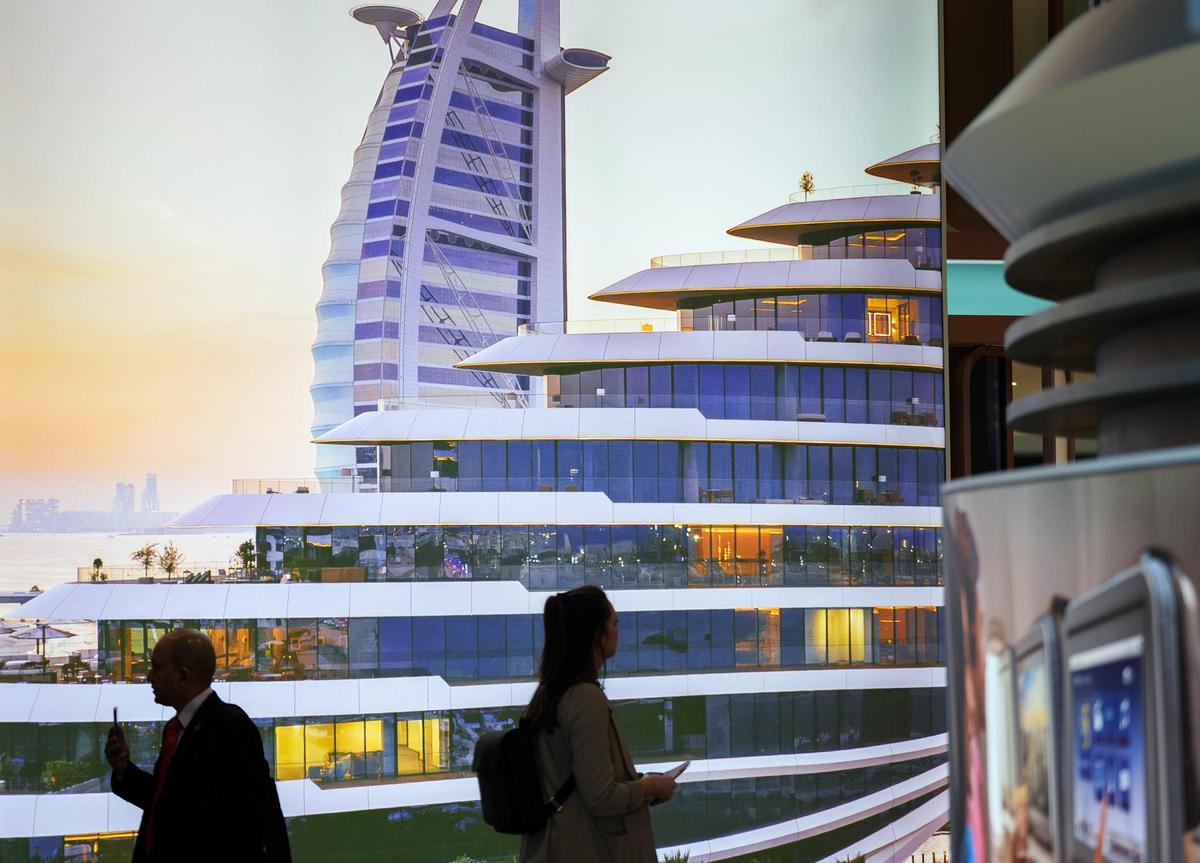 Messebesucher gehen am Eröffnungstag der Internationalen Tourismus-Börse (ITB) am Stand von Dubai vor einem Bildschirm vorbei, auf dem das Hotel Burij al Arab zu sehen ist.