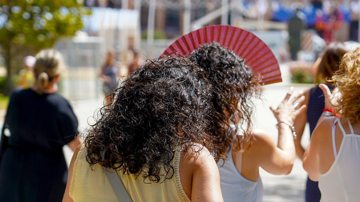 Dos mujeres con un abanicos pasean por el Parque de Maria Luisa, en Sevilla.