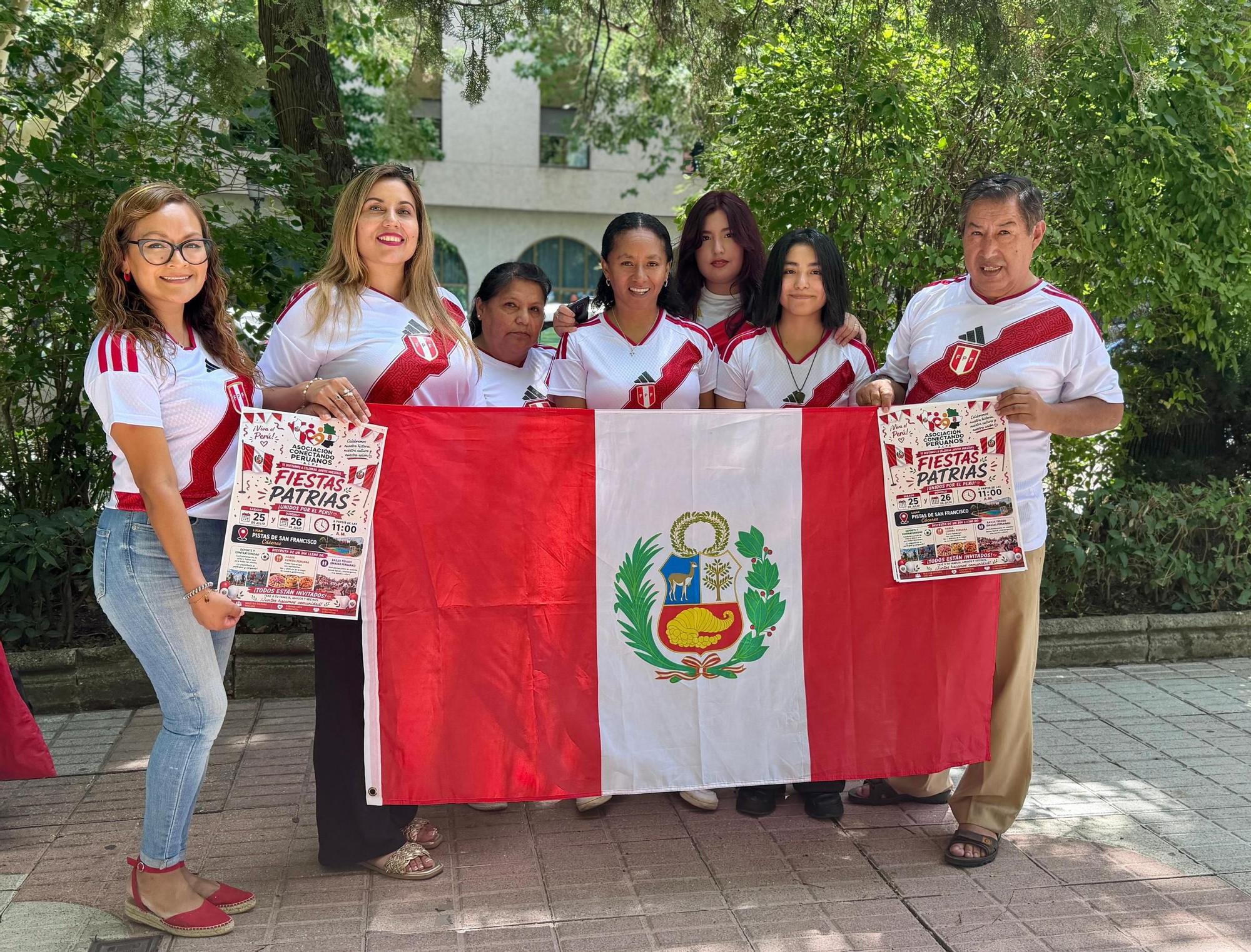 Los miembros de la Asociación Conectando Peruanos en Extremadura, con la bandera peruana y los carteles de la celebración prevista en San Francisco.