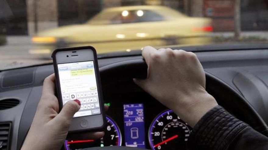 Una conductora escribe un mensaje en el móvil mientras conduce.