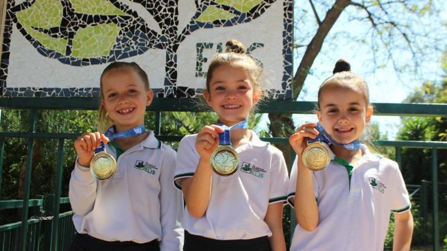 Tres pequeñas alumnas muestran con orgullo sus medallas.  | L.O.