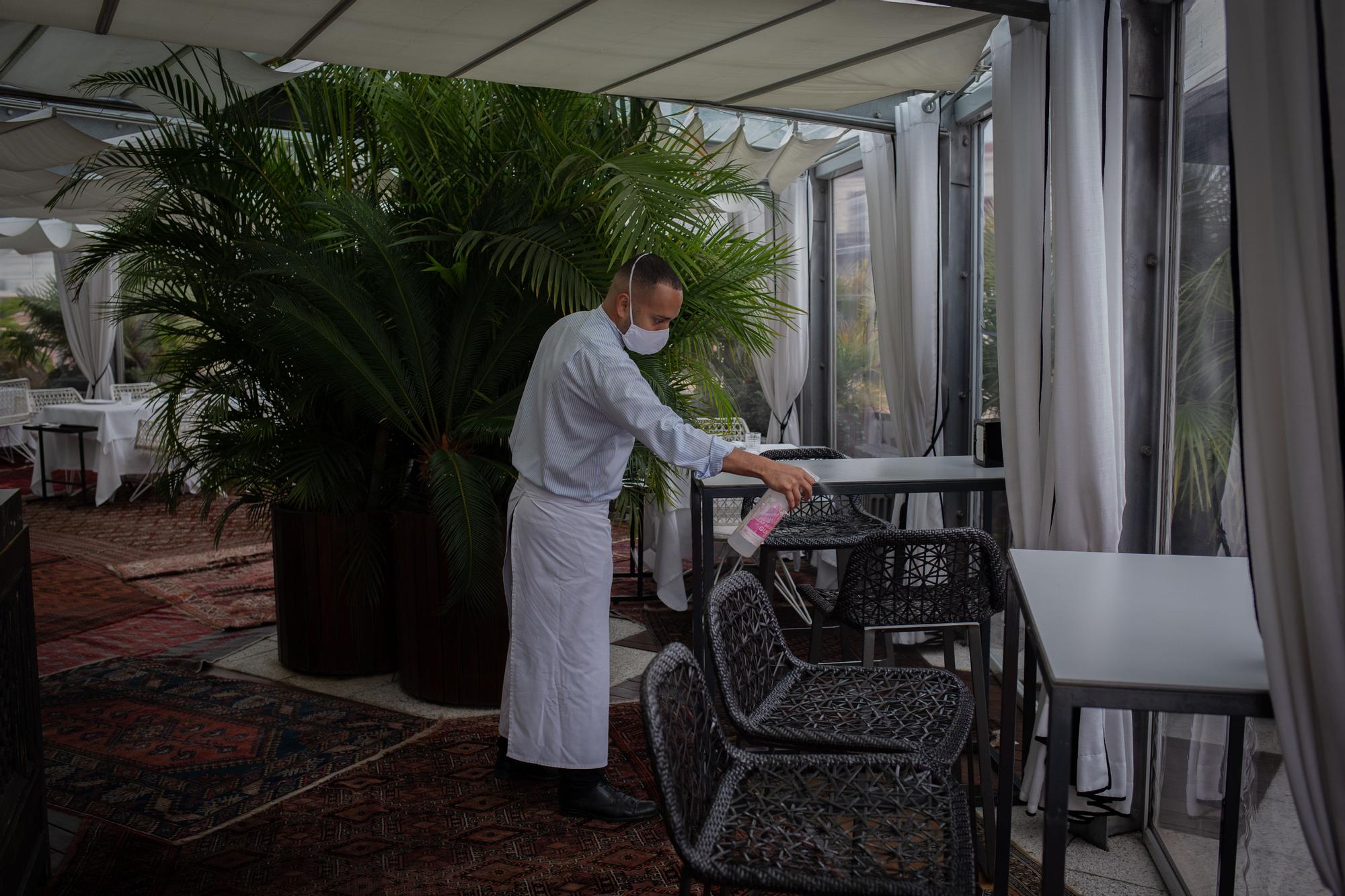 Un camarero limpia una de las mesas del Hotel Claris, en Barcelona, para evitar la transmisión de coronavirus.